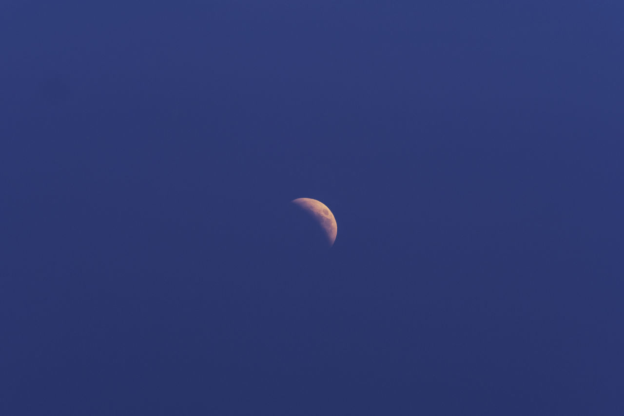 LOW ANGLE VIEW OF MOON IN BLUE SKY