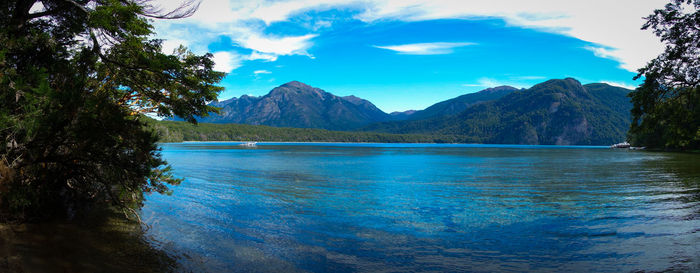 Scenic view of lake and mountains against blue sky