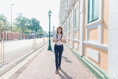 Full length of woman standing on mobile phone in city