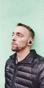 Portrait of young man looking away against wall