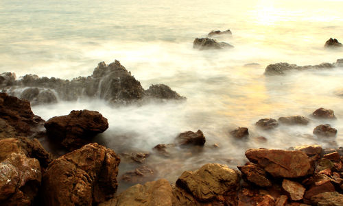 Scenic view of rocks in sea against sky