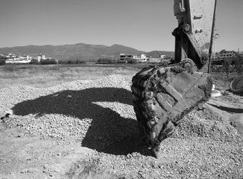 Cropped image of bulldozer over stones against clear sky