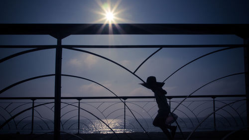 Silhouette boy playing against sky during sunset