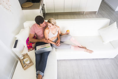 High angle view of man and woman sitting on sofa at home