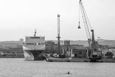 Cranes at harbor against sky