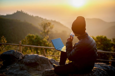 Man photographing on mountain during sunset