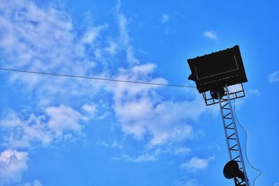 Low angle view of silhouette telephone pole against blue sky