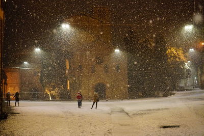 People walking on street in city during winter at night