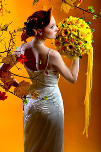 Young woman with yellow flower against white background
