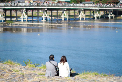 Rear view of couple sitting on riverbank