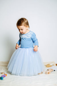 Cute baby girl in blue princess dress playing with toys at home. kids dresses for prom and birthday