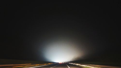 Light trails on road against sky at night