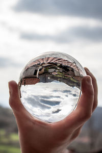 Close-up of person holding crystal glass against sky