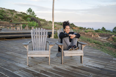 Rear view of woman sitting on wooden wall