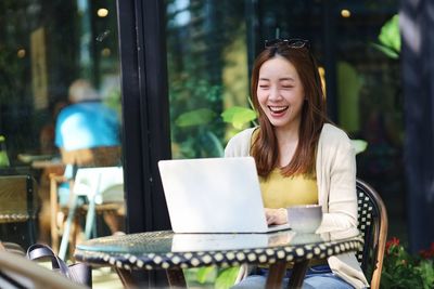 Young woman using laptop at cafe