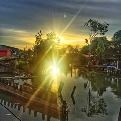 People by swimming pool against sky during sunset