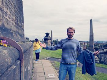 Rear view of men standing against sky in city