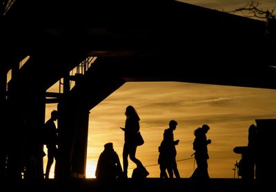 Silhouette people at beach against sky during sunset