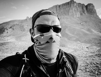 Portrait of man wearing sunglasses while standing against mountain