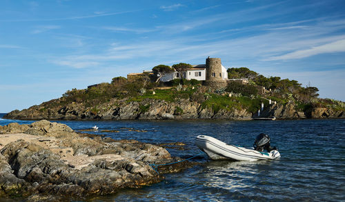 Boat in sea by rocks against sky