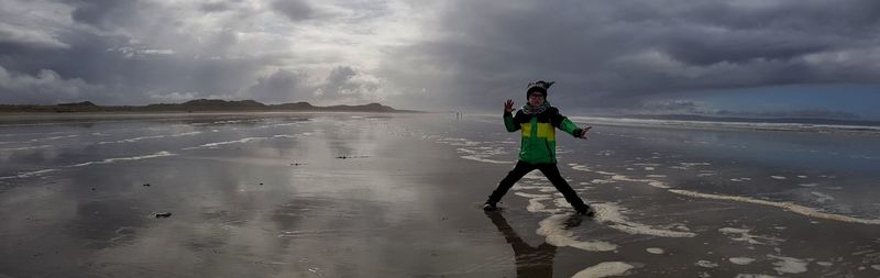 Boy posing at beach against sky