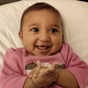 Portrait of smiling girl holding baby on bed
