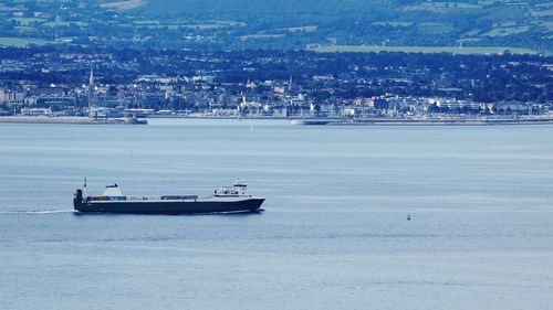 Sailboats in sea against city