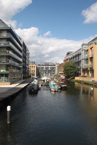 Boats moored on river by buildings in city against sky