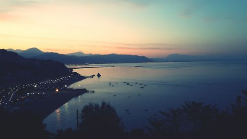 High angle view of sea and silhouette mountains at sunset