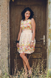 Portrait of woman standing against door