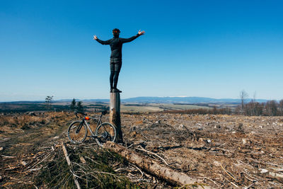 Man with arms outstretched on field against clear sky