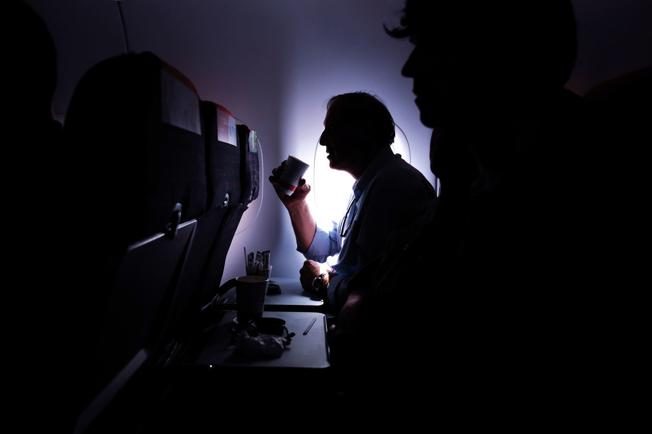 FULL LENGTH OF MAN SITTING IN ILLUMINATED UNDERGROUND