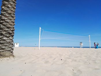 A beach, a trunk of a palm and a volleyball net