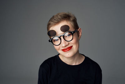 Portrait of young man wearing sunglasses against gray background