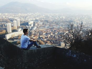 High angle view of man sitting on buildings in city