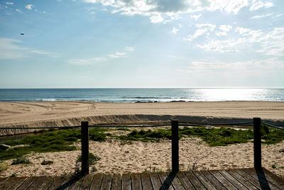 Wooden posts on beach against sky