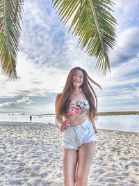 Young woman smiling while standing on beach