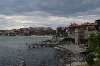 Buildings in town against cloudy sky