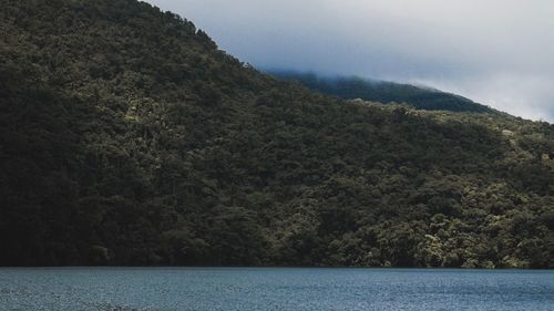 Scenic view of mountain by sea against sky