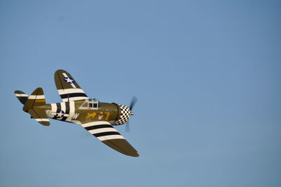 Low angle view of airplane flying against clear blue sky