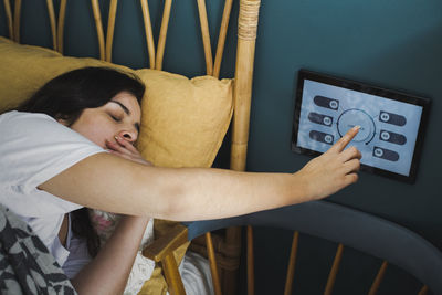 Woman yawning while using home automation device on wall in bedroom