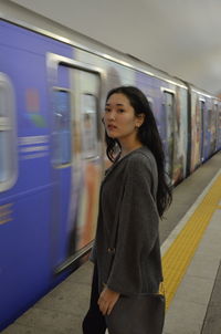 Woman standing by train at railroad station