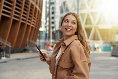 Smiling woman using mobile phone on street