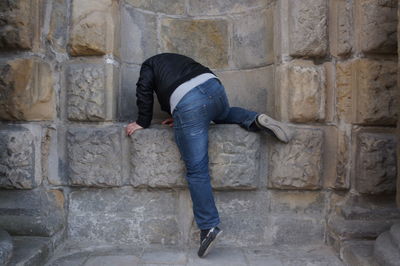 Rear view of man climbing stone wall