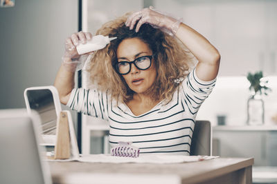 Portrait of young woman using mobile phone while sitting on table