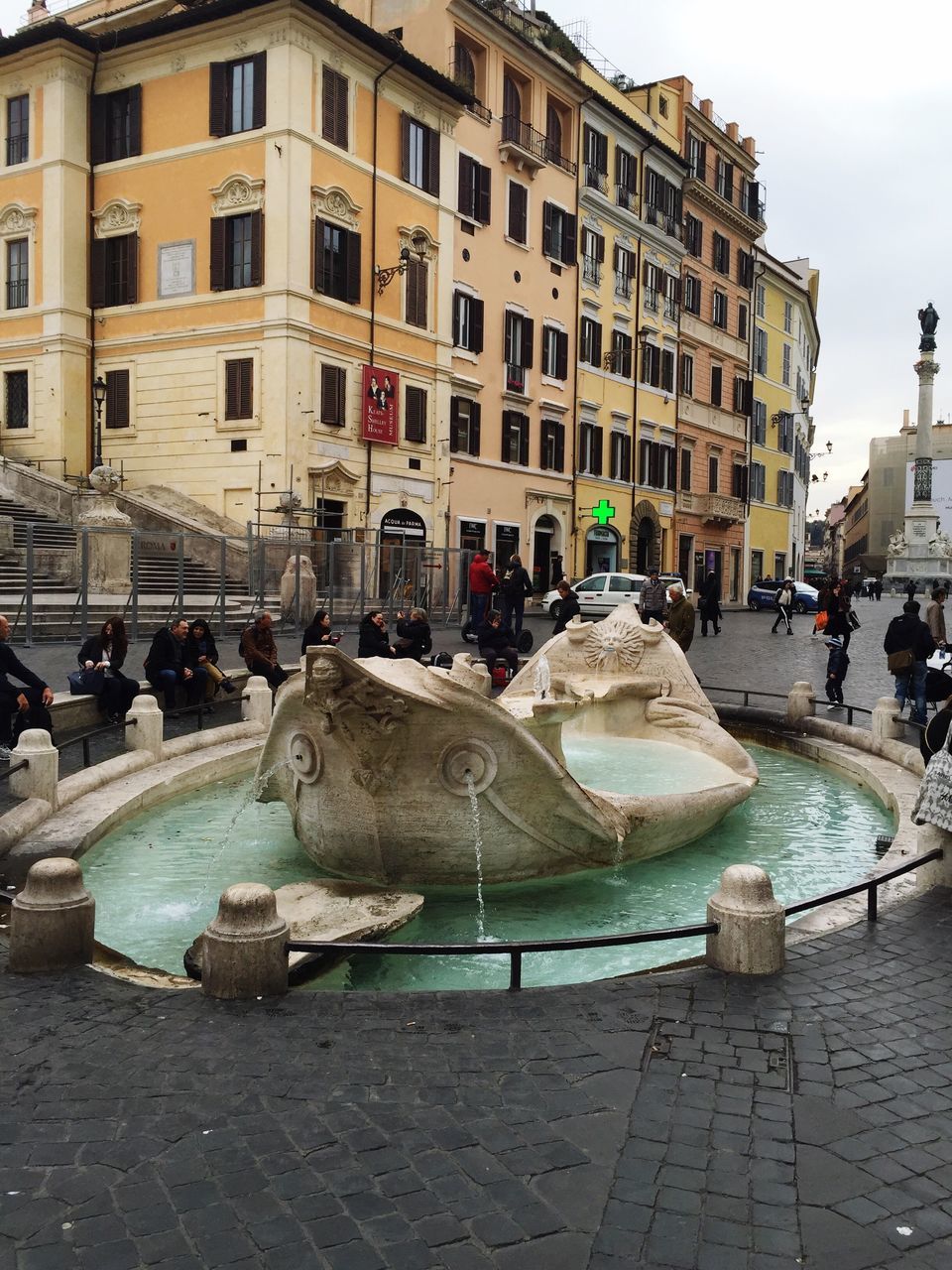 building exterior, architecture, built structure, city, large group of people, city life, water, men, person, street, lifestyles, leisure activity, mixed age range, incidental people, fountain, town square, building, city street, transportation