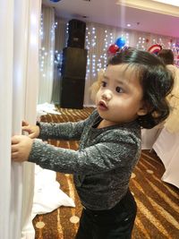 Cute girl looking away while standing at home