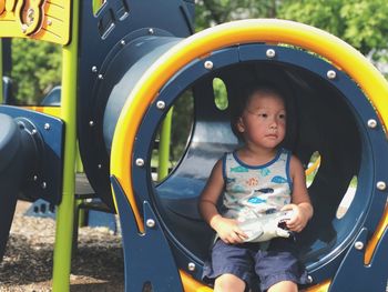 Boy sitting in slide at playground
