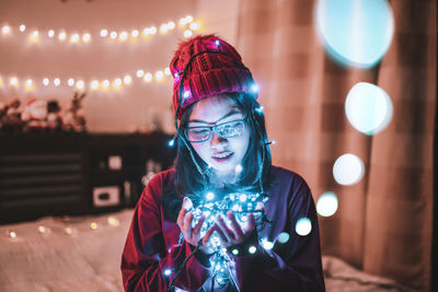 Portrait of smiling woman standing against illuminated lights