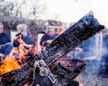 Close-up of burning wood against people